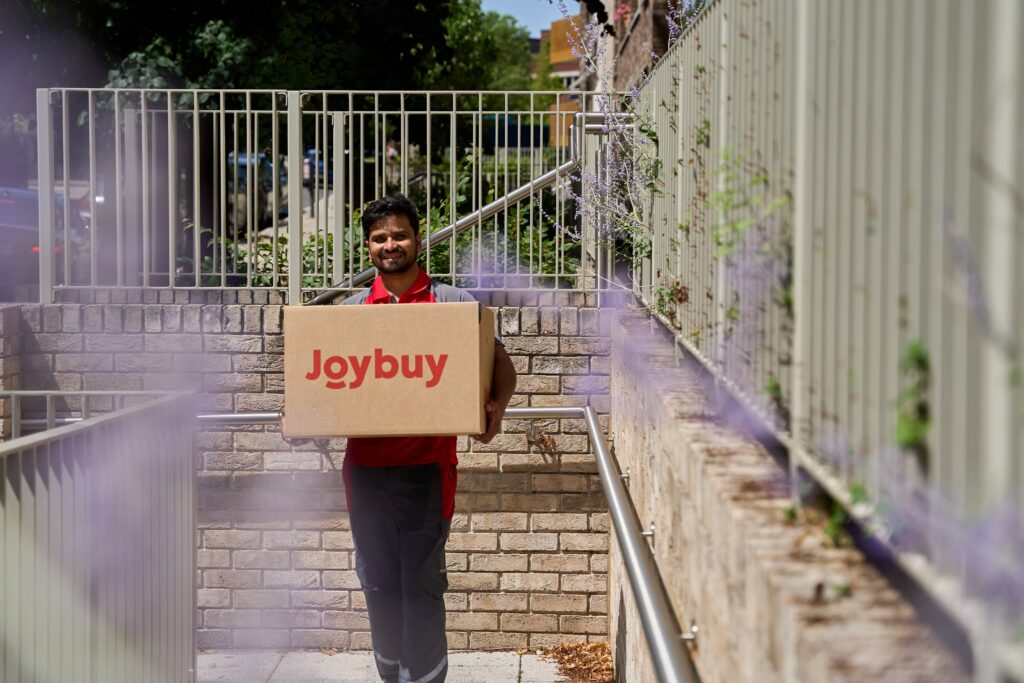 Courier carrying a Joybuy delivery box outdoors